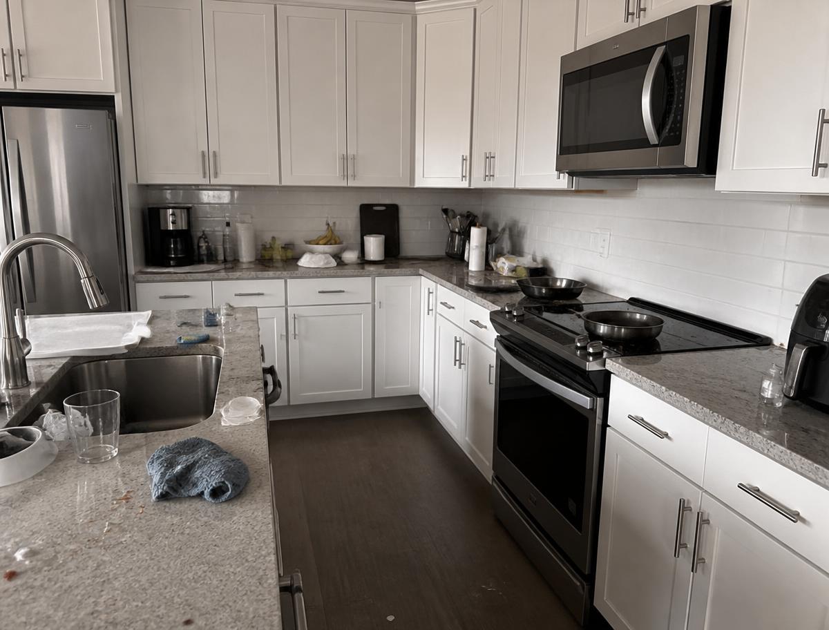 Kitchen before a deep clean with cluttered counters and cooking residue